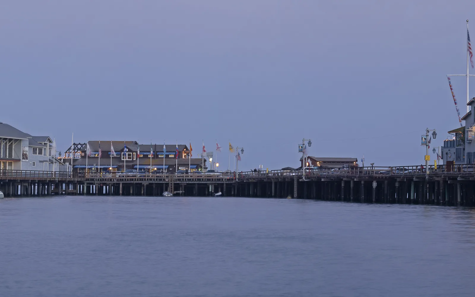 Stearns Wharf at dusk with evening light casting golden tones on the water and the structures of California's oldest working wood wharf